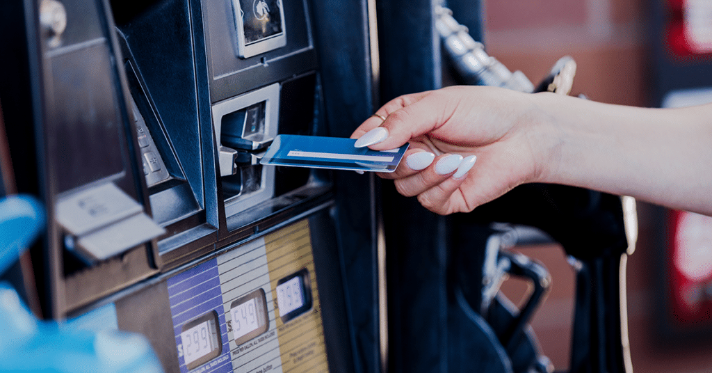 woman paying for fuel at a fuel pump with a credit card evoking the question how much do fuel cards cost?