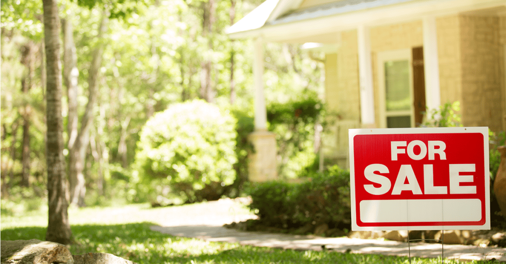 image of home with for sale sign set in front lawn, evoking Increased Mortgage Interest Rates