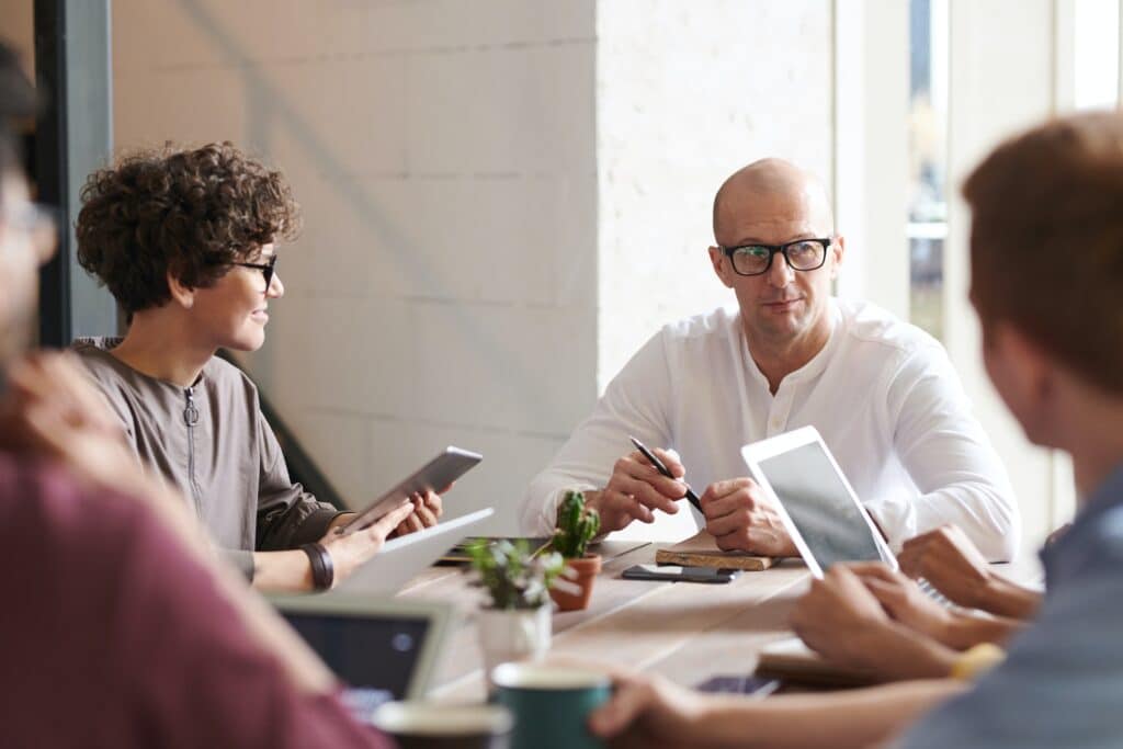 Photo of man sitting in front of co-workers in a meeting room