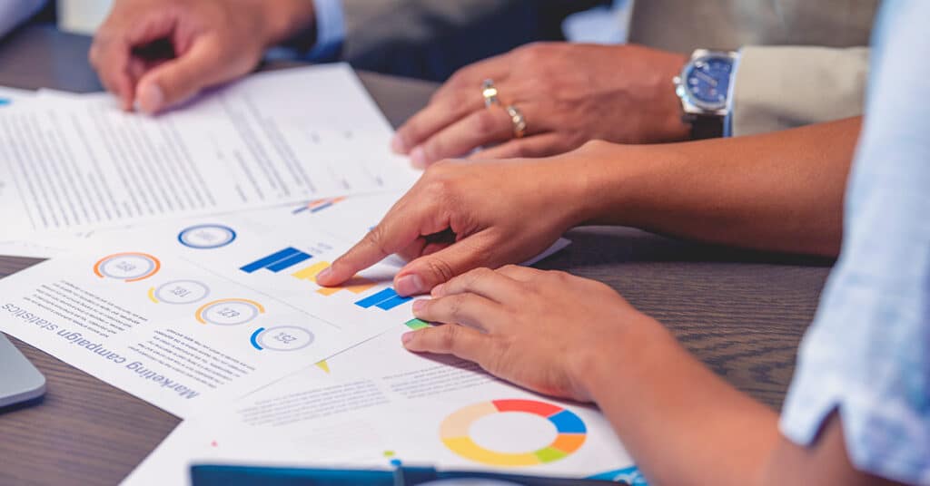 business people at table of charts and graphs of data evoking core-flex policies