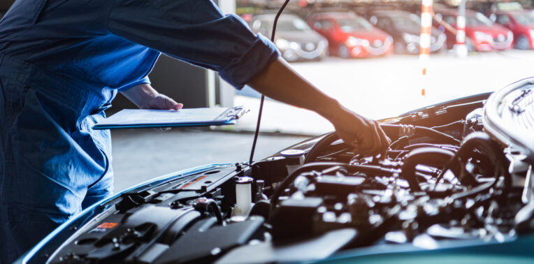 Car mechanic holding clipboard and checking to maintenance vehicle by customer claim order in auto repair shop garage. Engine repair service. People occupation and business job. Automobile technician